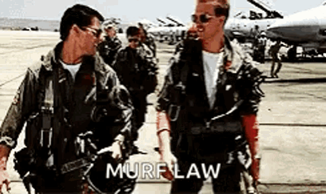 two men in military uniforms are standing next to each other on a runway with the word murf law written on the bottom .