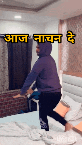 a man in a purple hoodie is jumping on a bed with a caption that says " आज नाचन है "