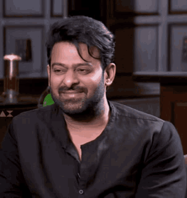 a man with a beard is wearing a black shirt and smiling .