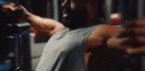 a man is using a machine in a gym to train his arms .