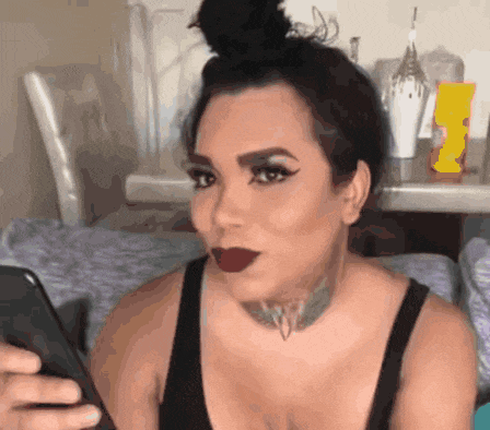 a woman with a tattoo on her neck is looking at her cell phone