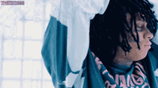 a man with dreadlocks is wearing a blue shirt that says ' swag ' on it