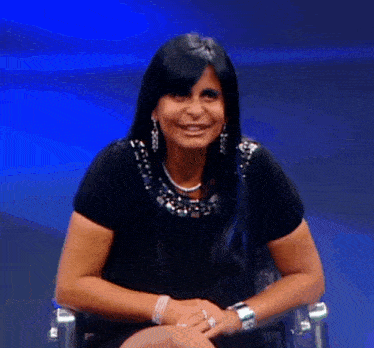 a woman with long black hair is smiling and wearing a necklace
