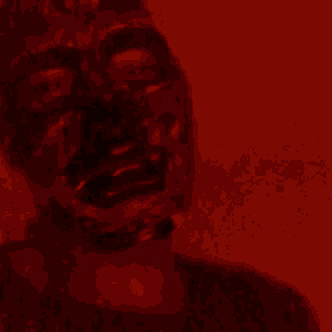 a close up of a person 's face in a dark room with a red light behind them .
