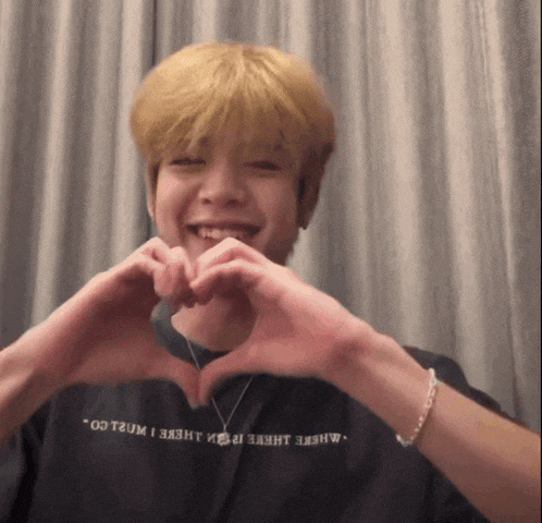 a man making a heart shape with his hands wearing a shirt that says where there i went
