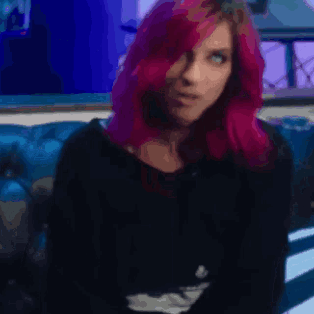 a woman with pink hair is wearing a black shirt and making a surprised face