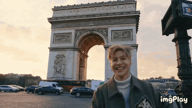 a man stands in front of a triumphal arch with a sign that says imgplay on it