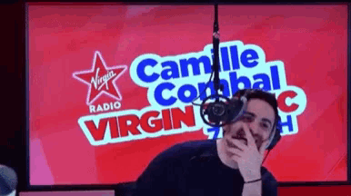 a man is standing in front of a virgin radio sign