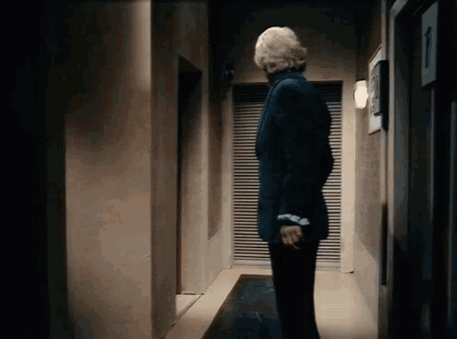 a man in a suit is standing in a hallway with shutters
