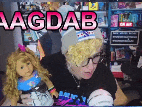 a person holding an american girl doll and a sign that says ' hagdab ' on it