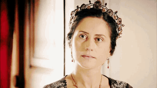 a woman wearing a tiara and earrings is looking at something