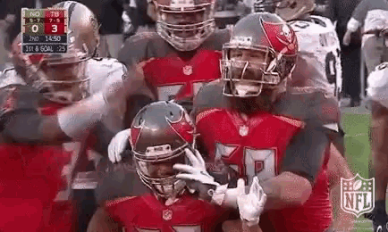 a group of football players are celebrating a touchdown on a field .