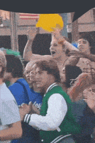 a man in a green jacket is holding a yellow sign