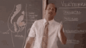 a man in a suit and tie is standing in front of a chalkboard and saying `` thank you '' .