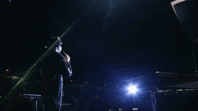 a man singing into a microphone with a blue light behind him