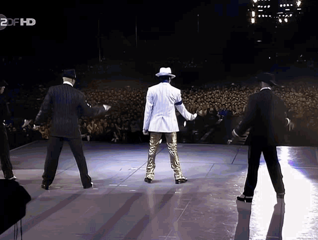 a group of men are dancing on a stage in front of a 2df hd advertisement