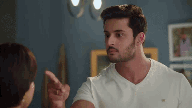 a man in a white t-shirt points at a woman