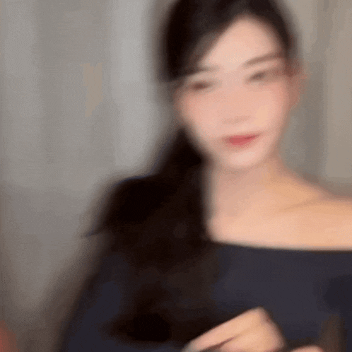 a blurry picture of a woman in a blue off the shoulder top with long hair .