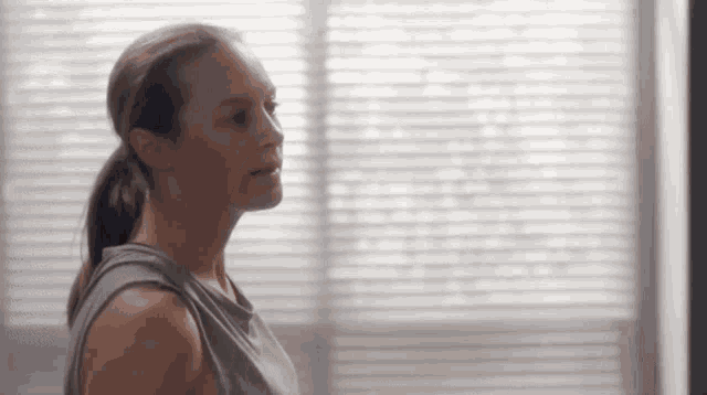 a woman in a ponytail is standing in front of a window .