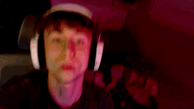 a young man wearing headphones is taking a selfie in a dark room