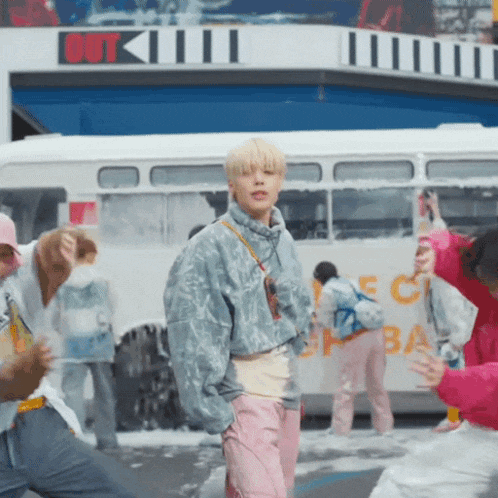 a group of people are dancing in front of a bus that says out