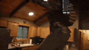 a person is dancing in a kitchen with a sign on the wall that says ' r '