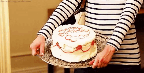 a woman in a striped shirt is holding a birthday cake