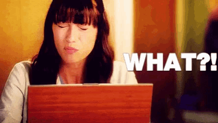 a woman is sitting in front of a laptop with the words what written on the screen
