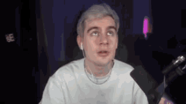 a man is sitting in front of a microphone wearing ear buds .