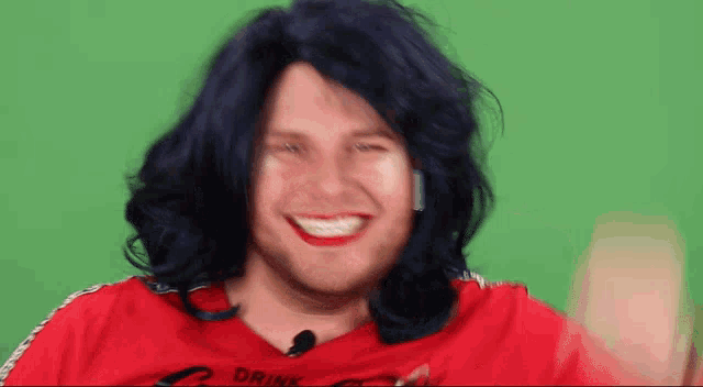 a man with blue hair and red lipstick is wearing a red shirt that says drink