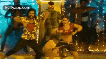 a group of people are dancing together on a stage in a room .