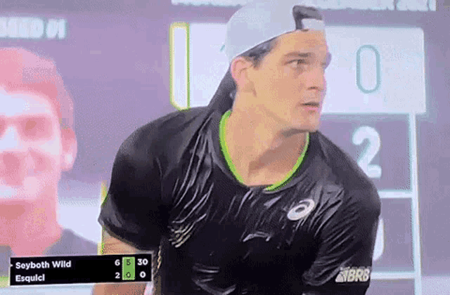 a man in a black shirt is standing in front of a scoreboard with the name say both wild on it