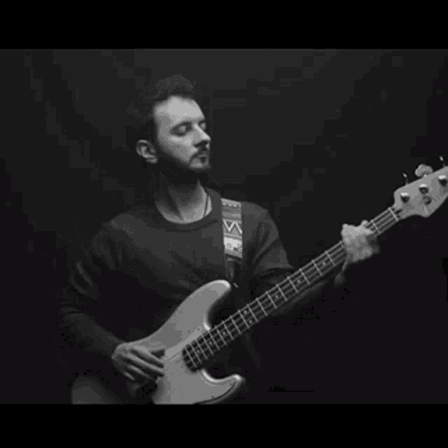 a man is playing a bass guitar in a dark room .
