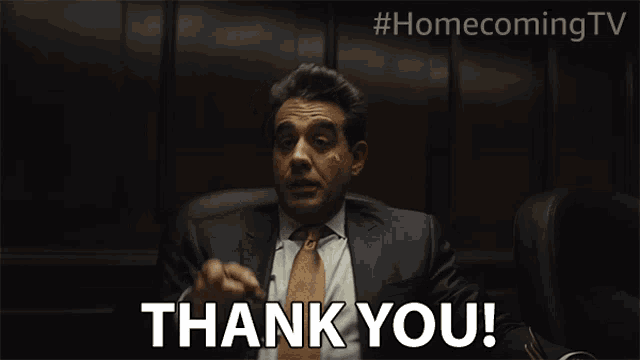 a man in a suit and tie is giving a thank you gesture