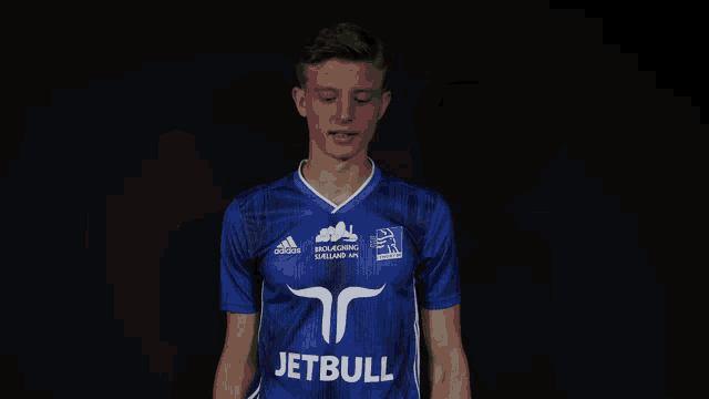 a man in a blue adidas shirt holds a bunch of white flowers in front of his face