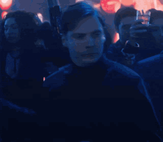 a group of people are standing in a dark room and one of them is holding a glass