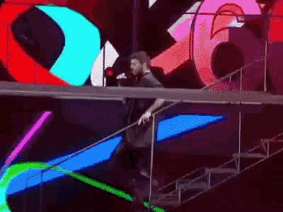 a man stands on a stage with a microphone in front of a sign that says ' x ' on it