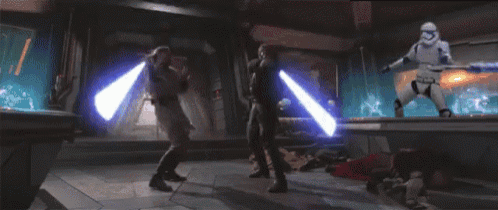 two people are fighting with lightsabers in a room while a storm trooper is standing in the background .