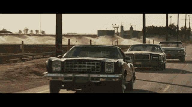 a group of cars are driving down a road and one of them has a license plate that starts with the letter g