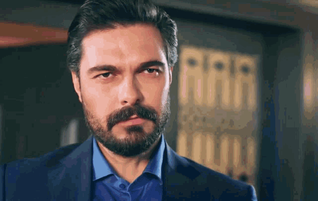 a man with a beard wearing a blue suit and blue shirt