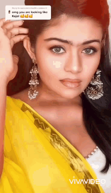 a woman wearing a yellow saree and earrings has a vivavideo watermark on the bottom