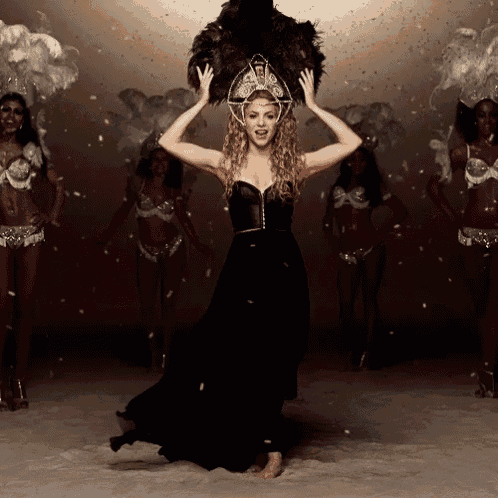 a woman in a black dress is dancing in front of a group of women