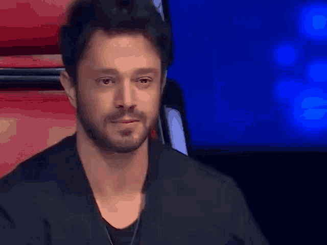 a man with a beard is sitting in a chair with his eyes closed and tears running down his face .
