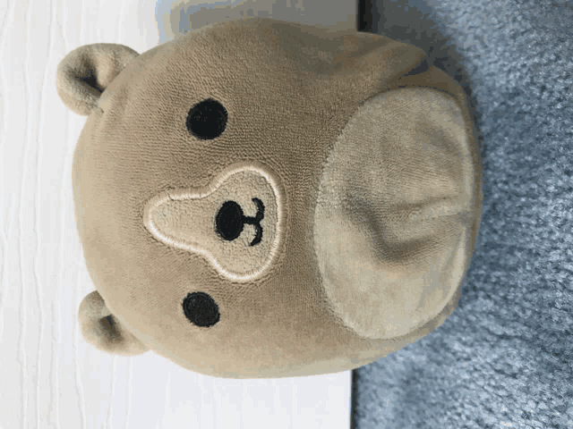 a stuffed teddy bear with a black embroidered face