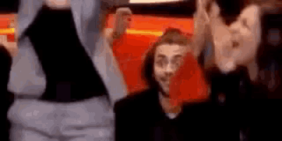 a group of people are standing next to each other in a room and laughing .