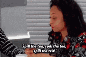 a woman is sitting at a table with a cup of tea and says spill the tea spill the tea spill the tea !