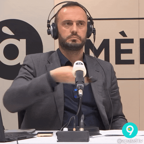 a man wearing headphones stands in front of a microphone in front of a sign that says a meir