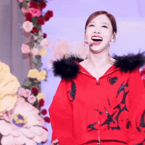 a woman in a red jacket with a black fur hood is laughing .