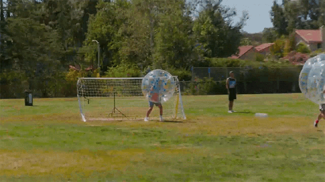 a group of people are playing bubble soccer on a soccer field