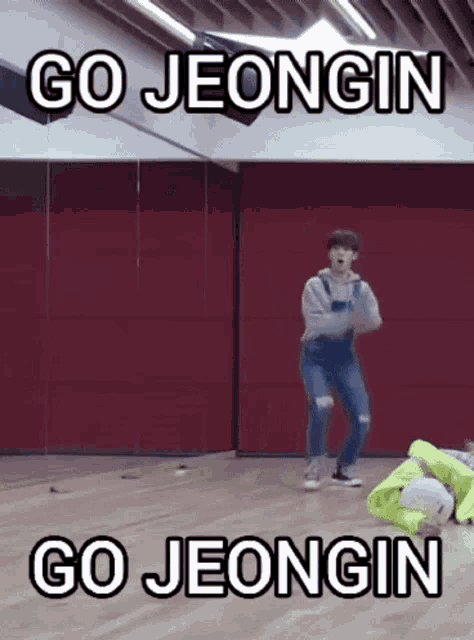 a man is dancing in a dance studio with the words `` go jeongin '' above him .